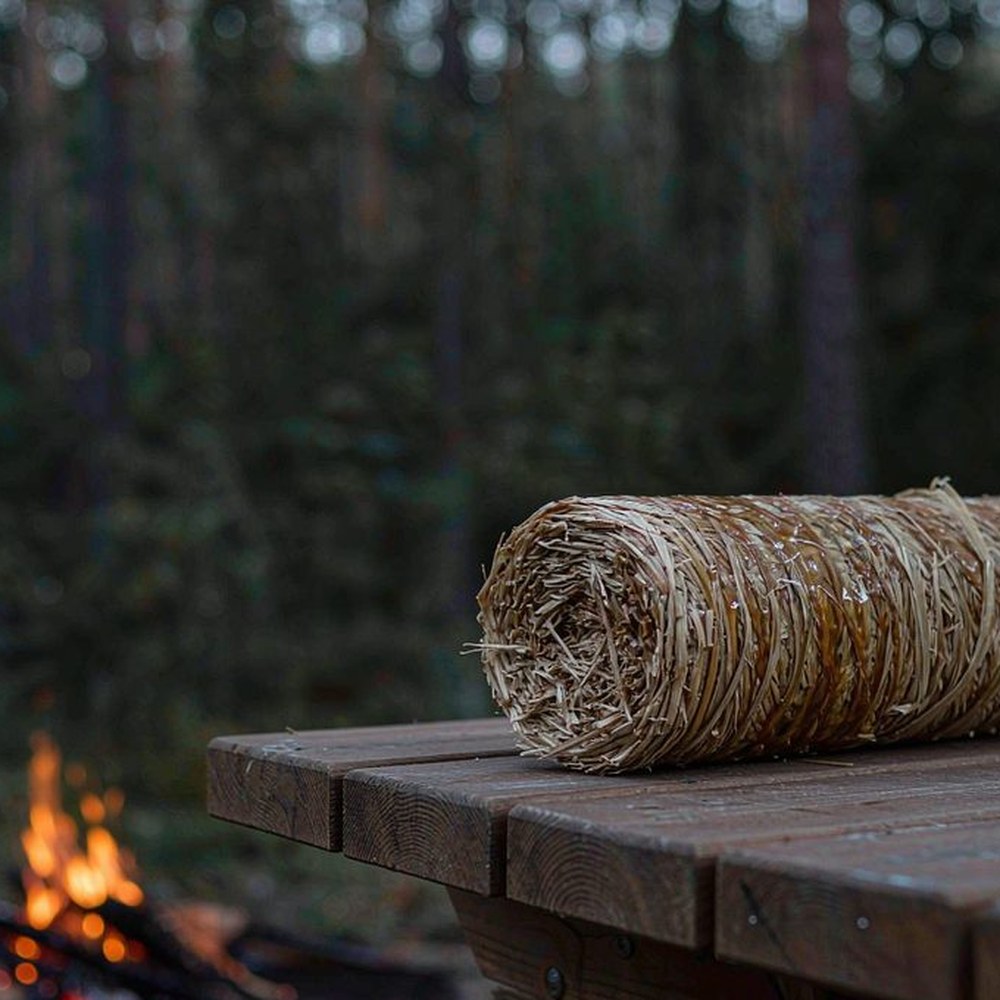 Classic waxed wood wool fire starter roll on a campsite table at dusk